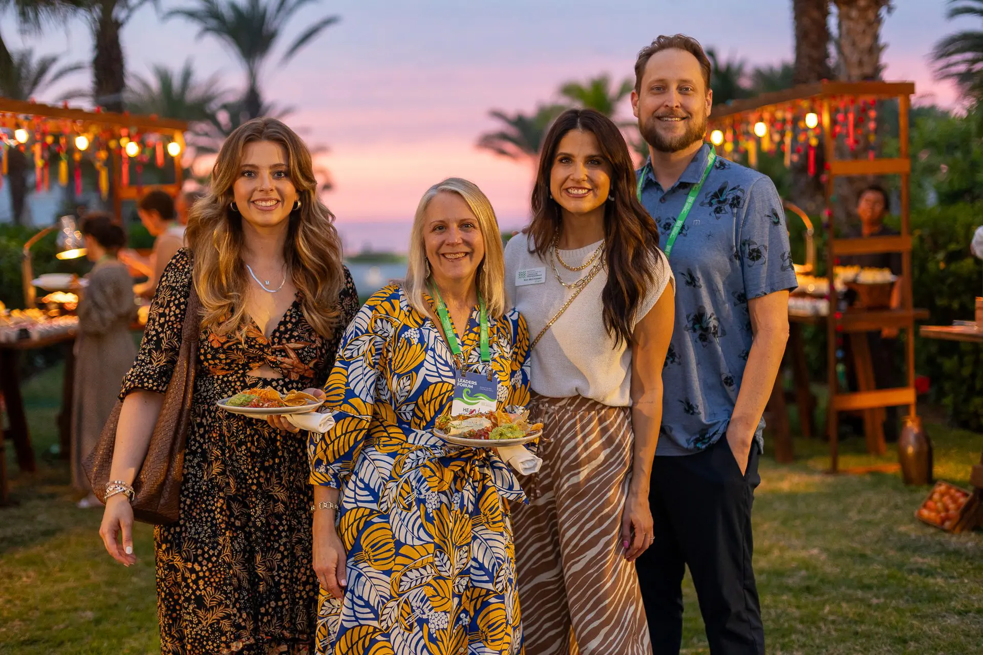 Grupo de personas posando al atardecer con atuendos elegantes.