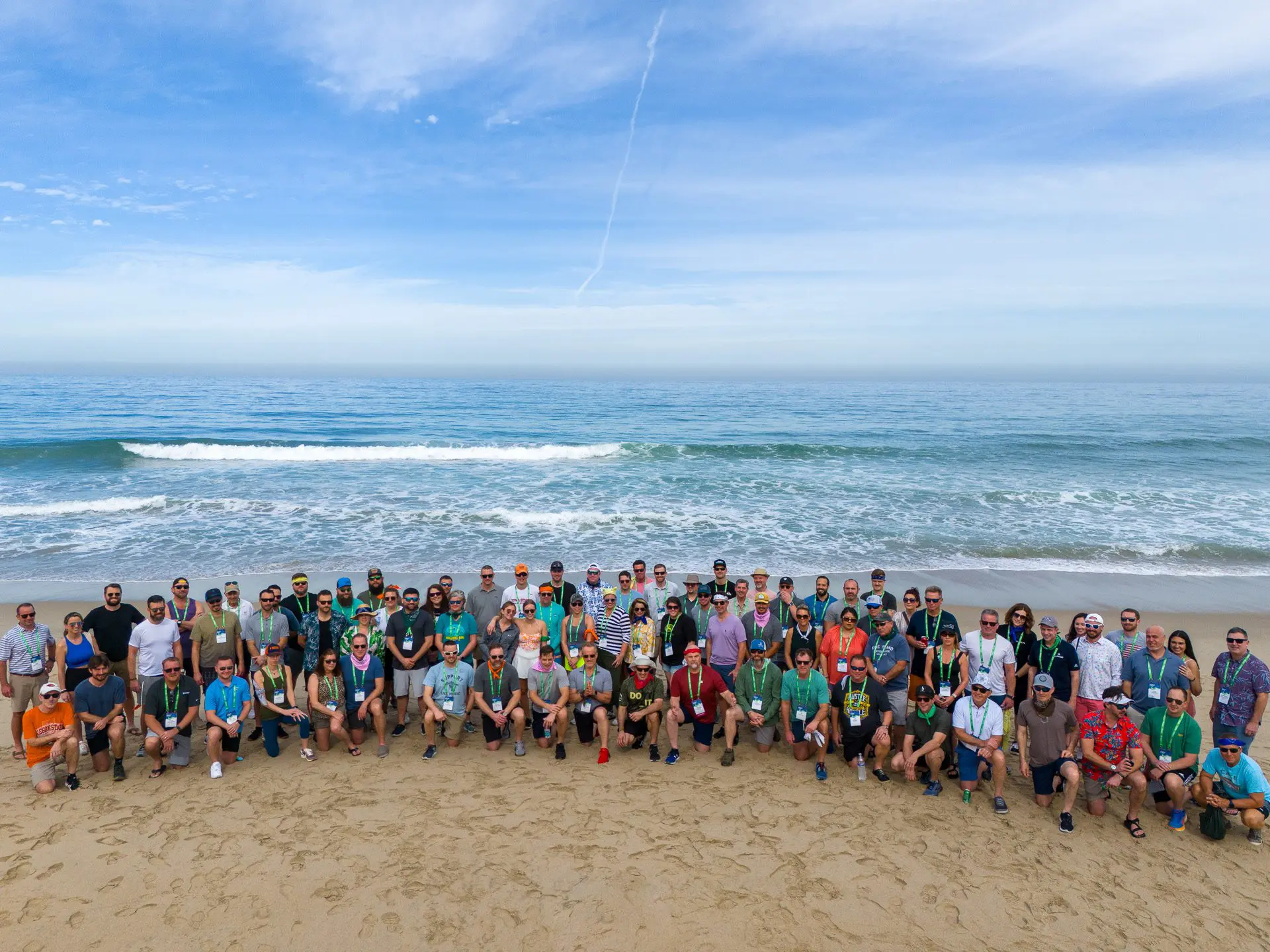 Gran grupo de asistentes a la conferencia se reunió en la playa para una foto grupal.