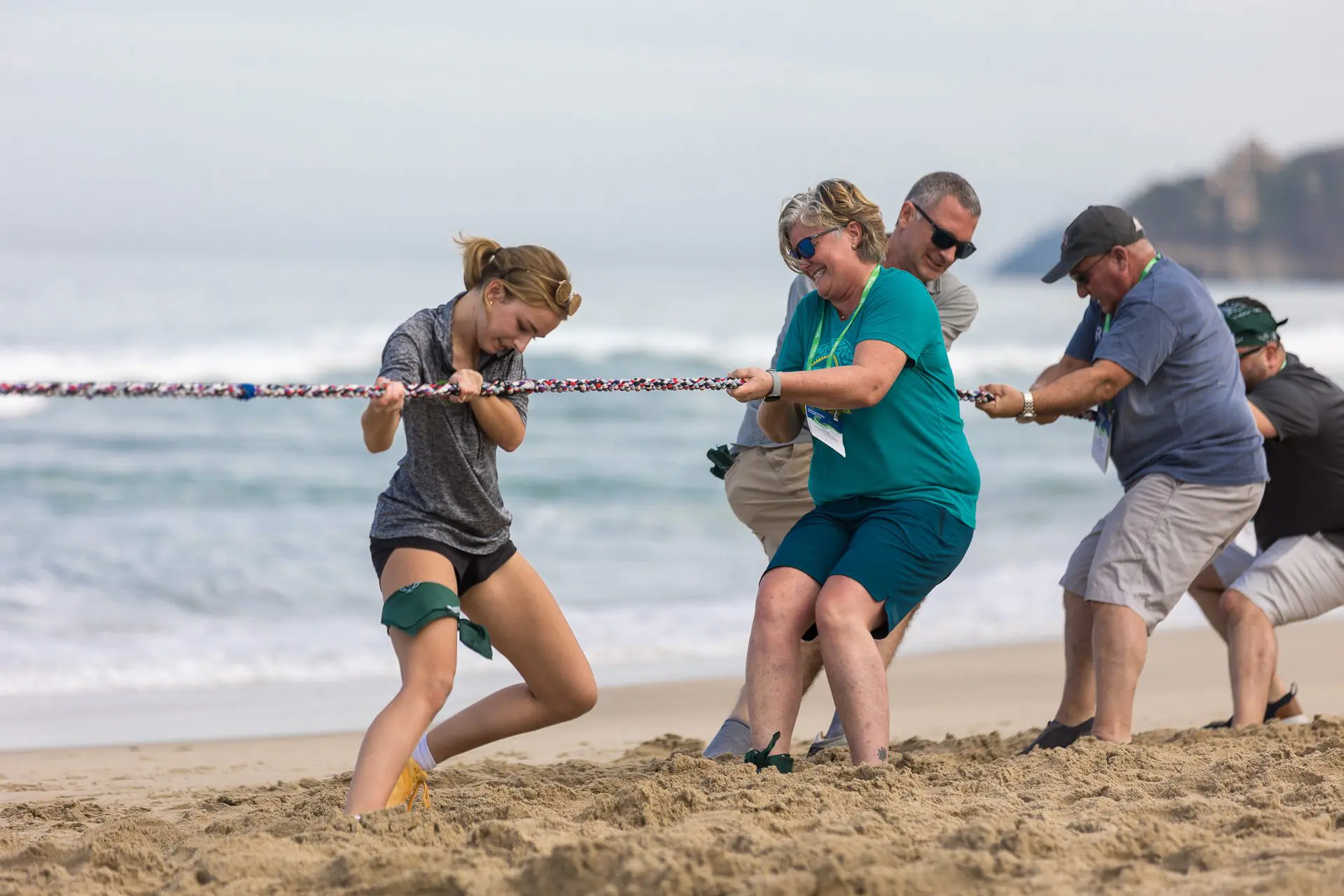 Dos mujeres tirando de una cuerda en un juego de tira y afloja en la playa.