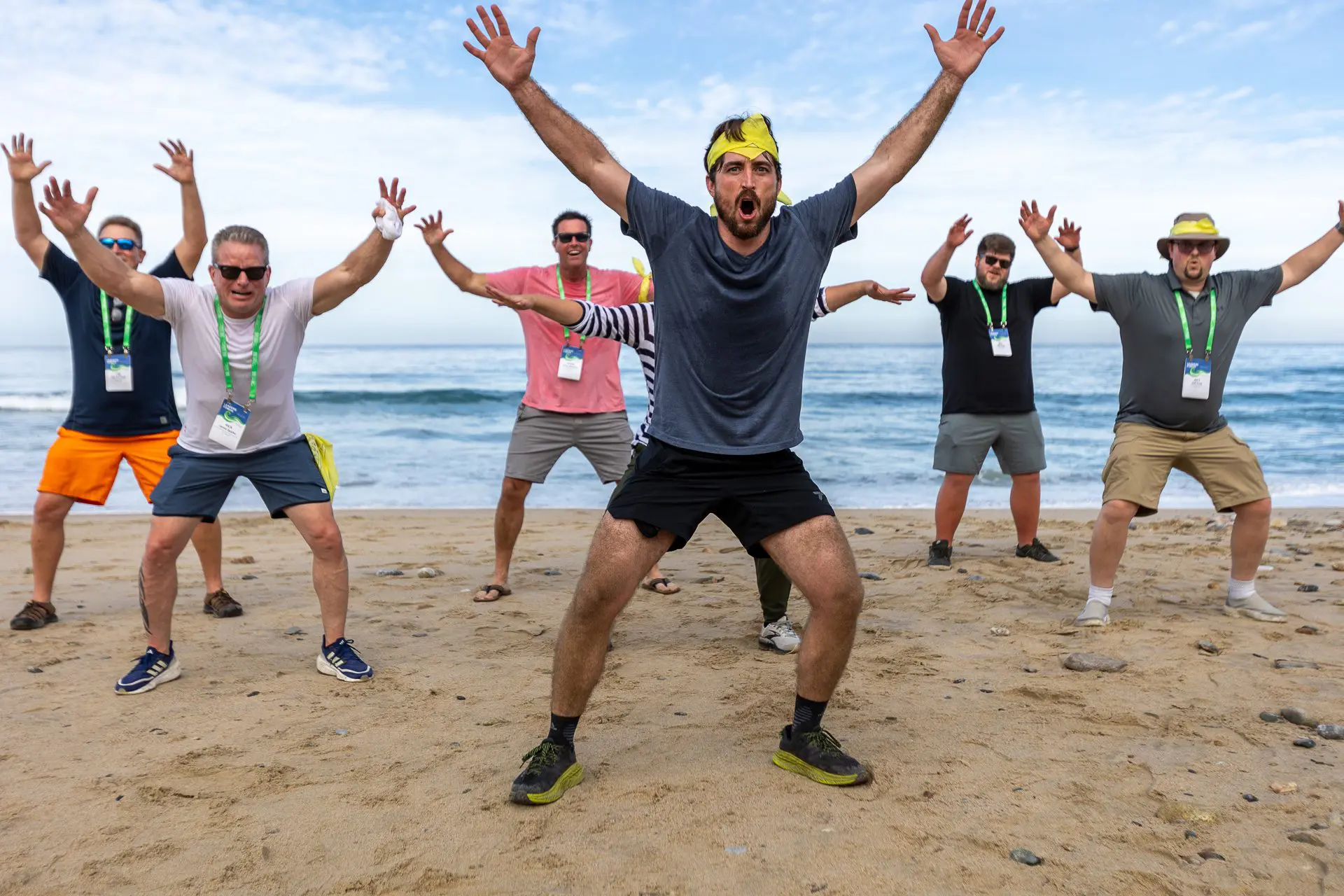 Grupo de personas levantando los brazos en señal de victoria en la playa.