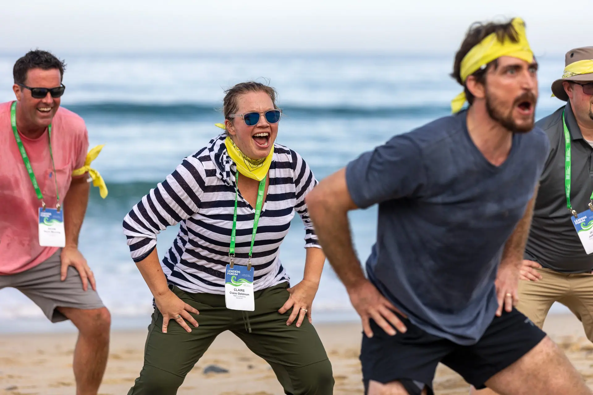 Actividad de team building en la playa con participantes luciendo diademas amarillas.
