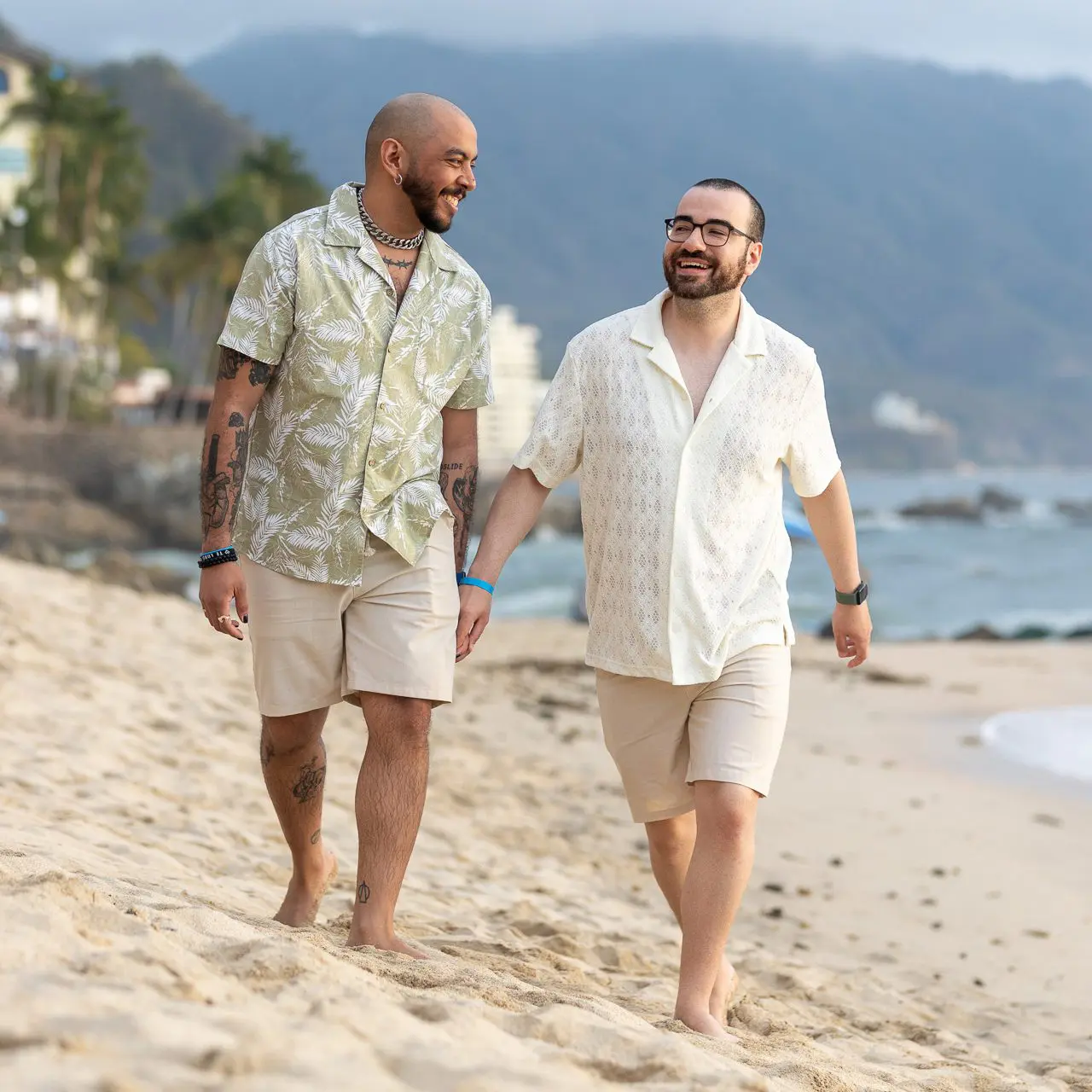 Casal gay recentemente noivo caminhando pela praia em Puerto Vallarta, México