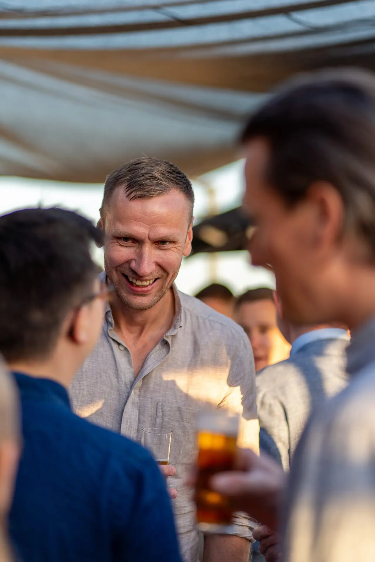 Los invitados se reúnen en un evento de networking frente al mar, tomando bebidas y participando en animadas conversaciones.