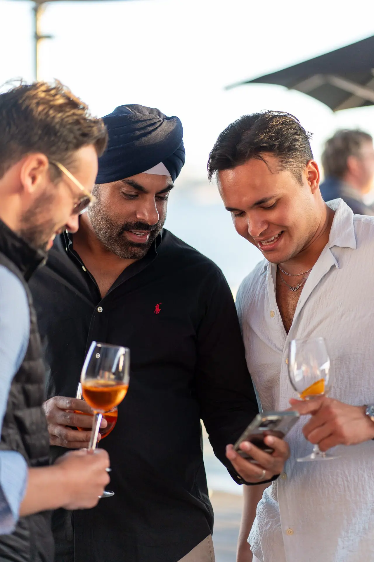 Los invitados se reúnen en un evento de networking frente al mar, tomando bebidas y participando en animadas conversaciones.