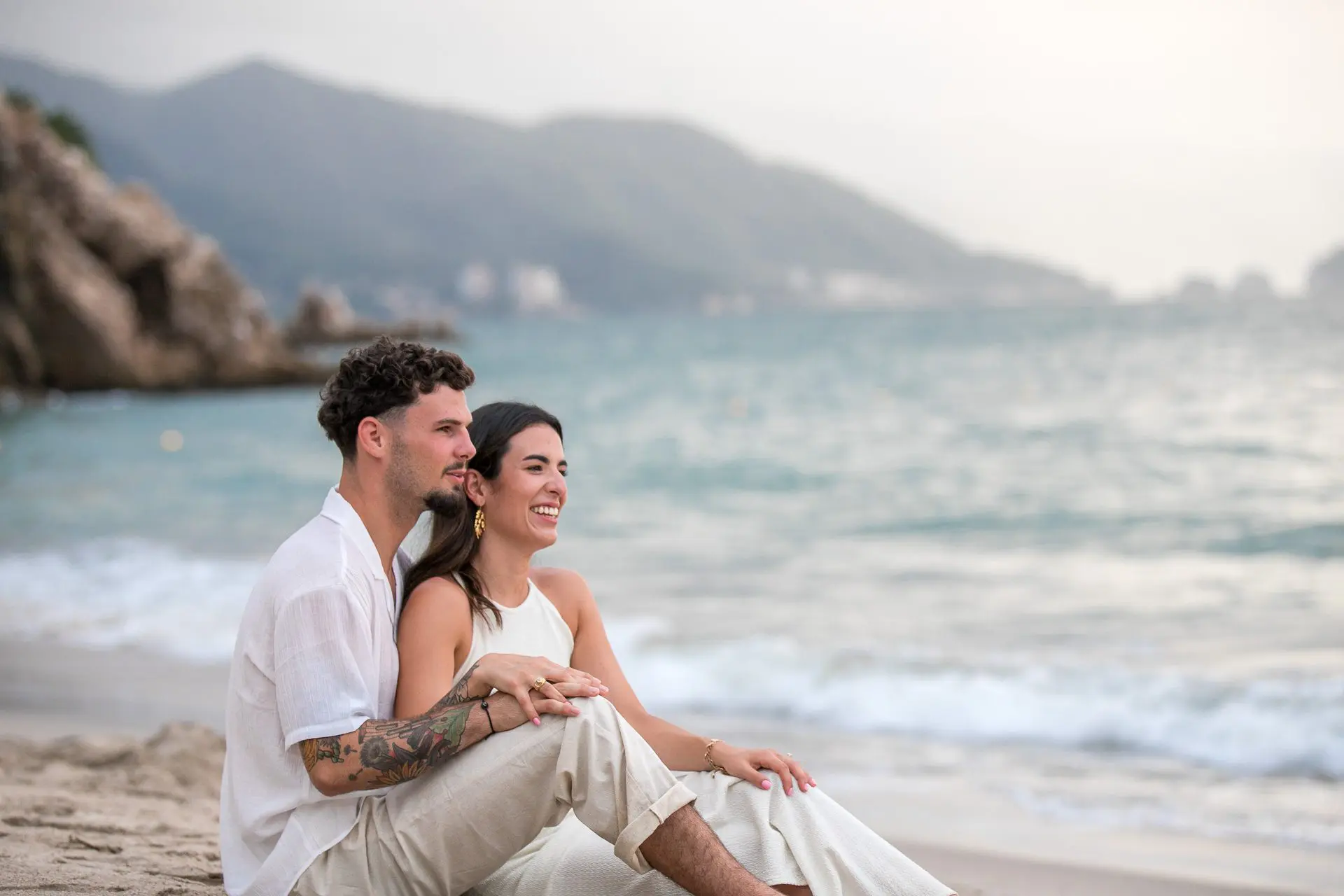 Eloped couple sit on a beach in Lisbon, Portugal