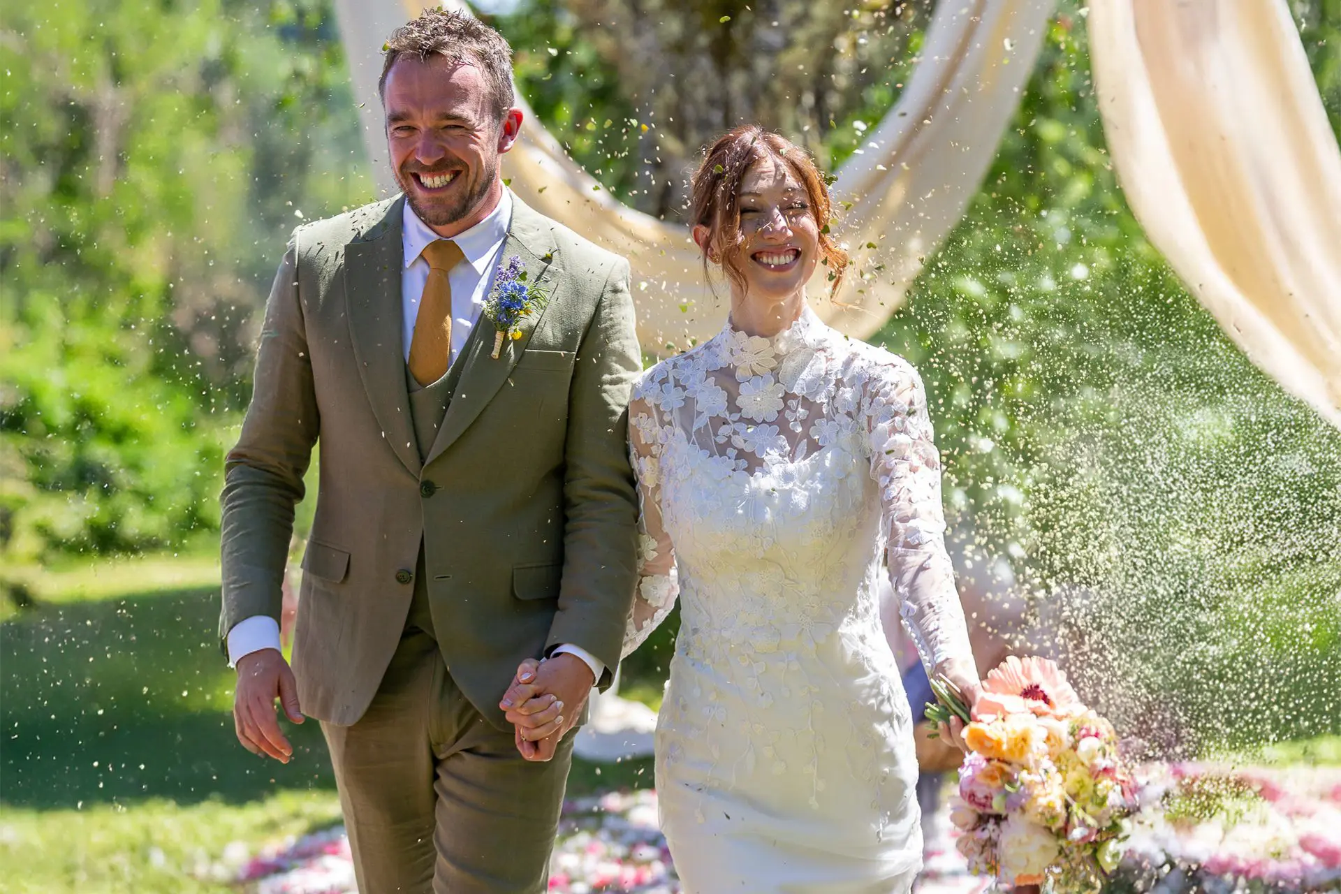 Bride and groom walk down the aisle as guests throw confetti at their destination wedding in France
