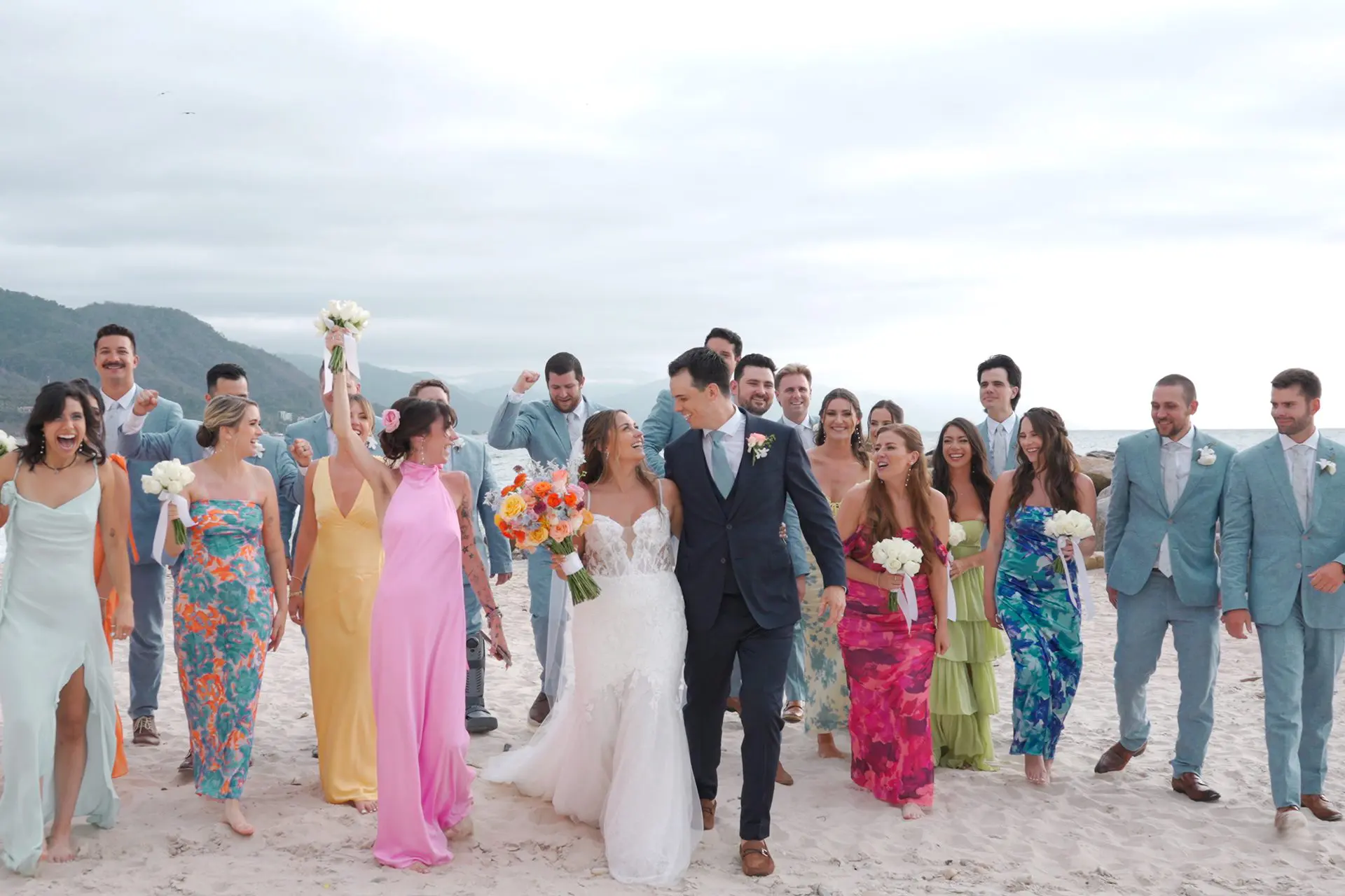 Bride and groom walk down the Puerto Vallarta beach with bridesmaids and groomsmen