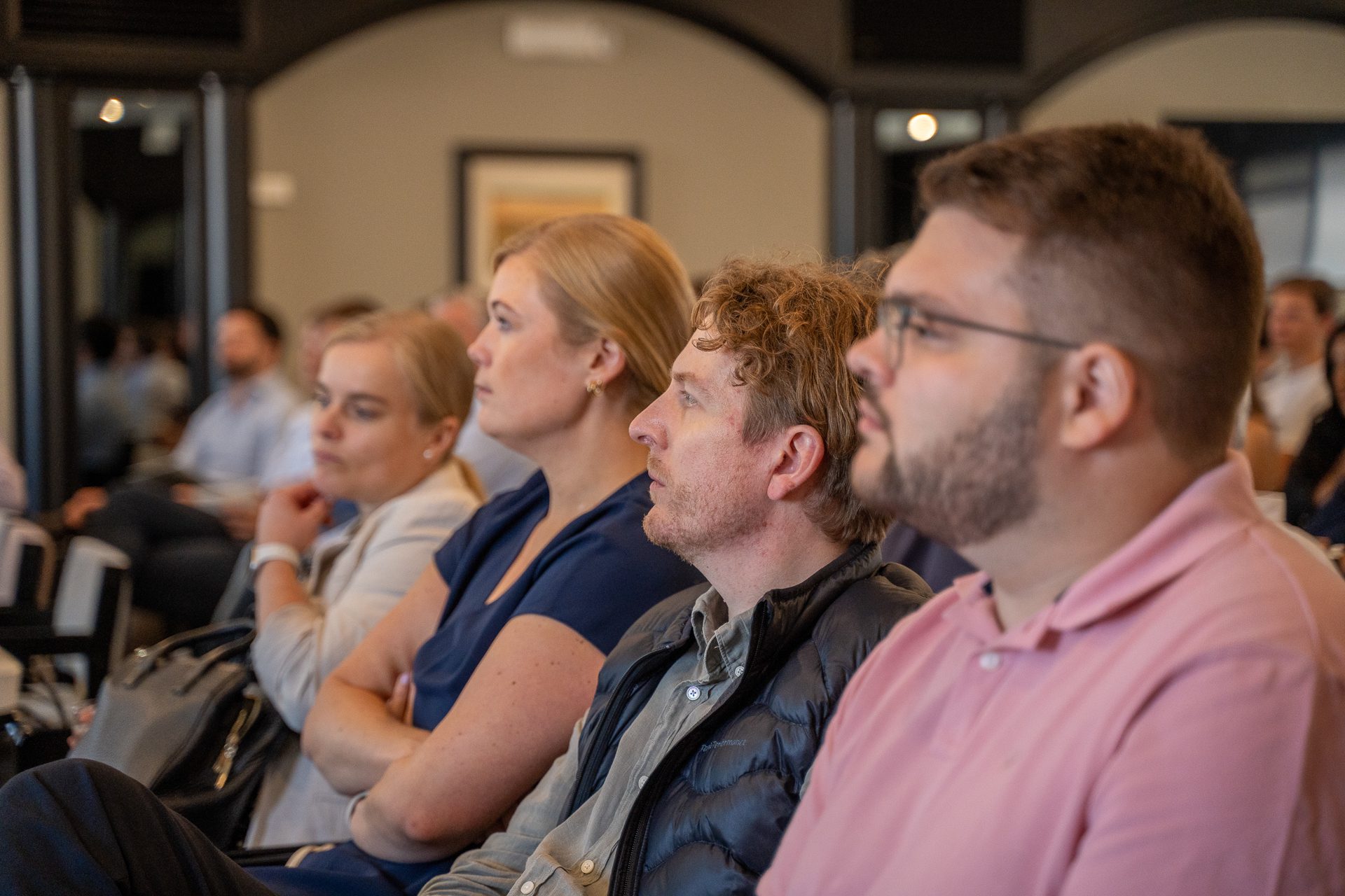 People attending a presentation in a corporate conference room, seated and attentive.