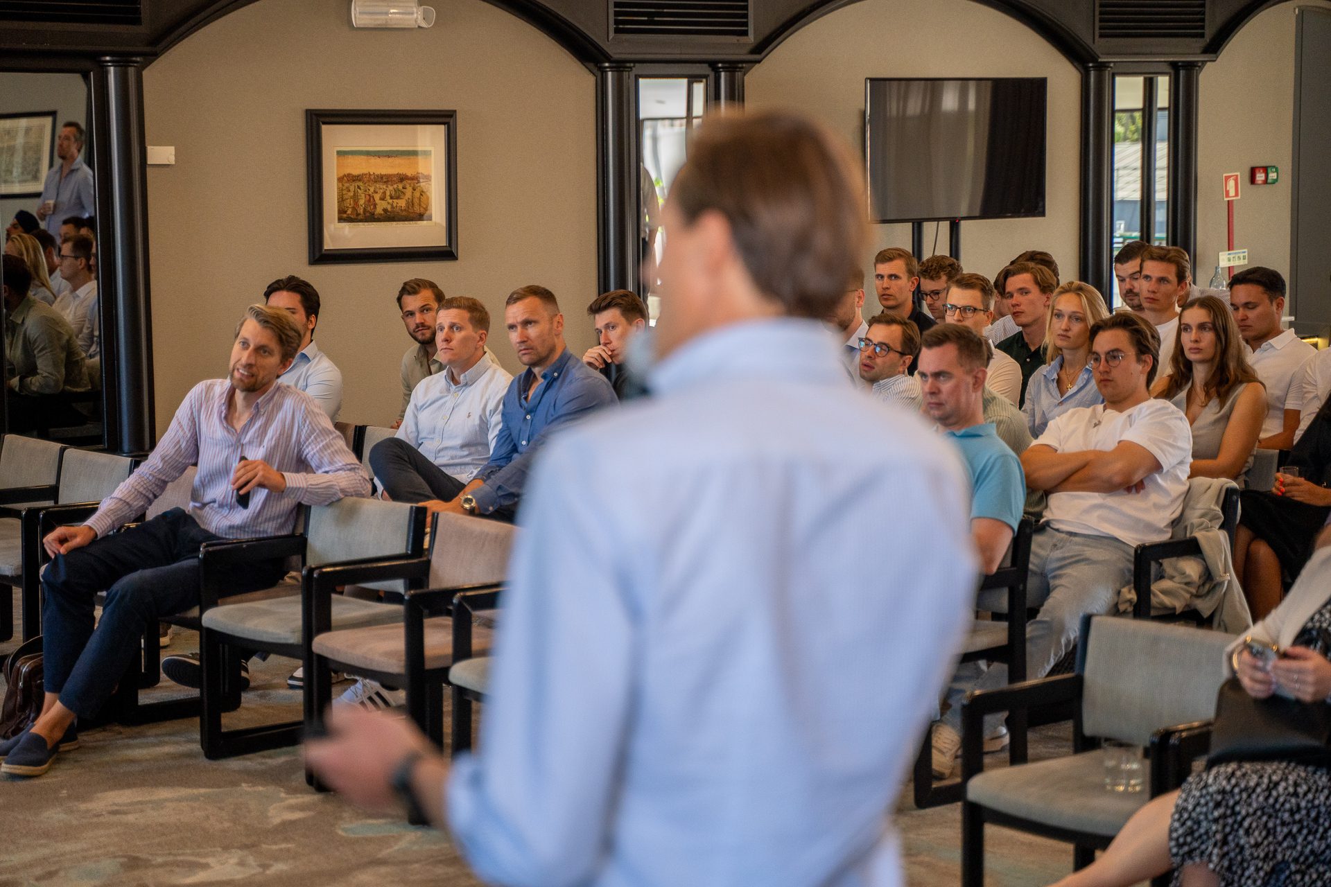 People attending a presentation in a corporate conference room, seated and attentive.