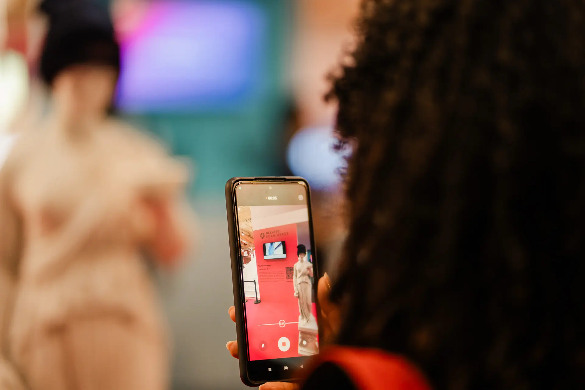 Una mujer tomando fotos con su teléfono en el evento corporativo de Niantic en Lisbon Web Summit 2024
